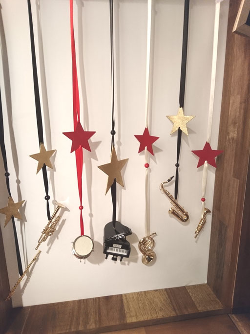 Fensterschmuck aus Mini-Musikinstrumenten - alle Instrumente sind am Seidenband aufgezogen und zusätzlich mit einem Metallstern versehen.