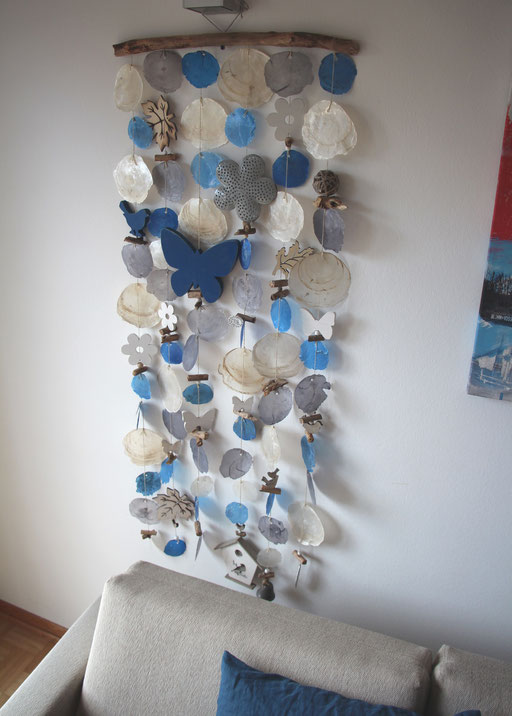 Capiz Wanddeko in blau und natur mit blauen Holzelementen.