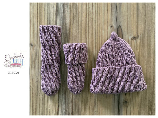handgestrickte Babyaccessoires - Socken und Mütze in Spiralmuster liegend in mauve