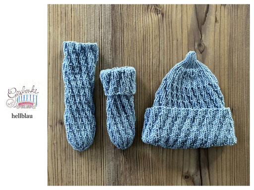 handgestrickte Babyaccessoires - Socken und Mütze in Spiralmuster liegend in hellblau