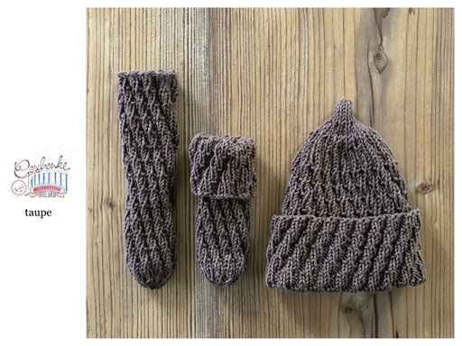 handgestrickte Babyaccessoires - Socken und Mütze in Spiralmuster liegend in taupe