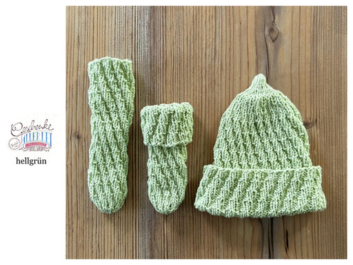 handgestrickte Babyaccessoires - Socken und Mütze in Spiralmuster liegend in hellgrün