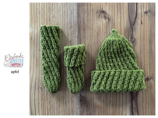 handgestrickte Babyaccessoires - Socken und Mütze in Spiralmuster liegend in apfel