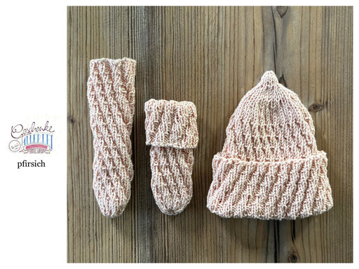 handgestrickte Babyaccessoires - Socken und Mütze in Spiralmuster liegend in pfirsich