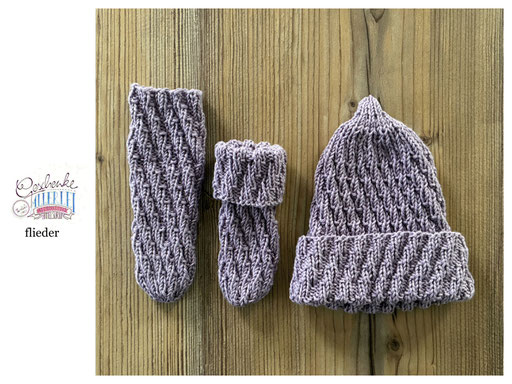 handgestrickte Babyaccessoires - Socken und Mütze in Spiralmuster liegend in flieder