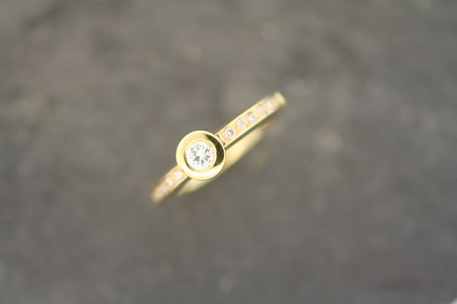 Ring in Gelbgold mit Brillant in Tellerfassung und kleinen Brillanten in der Ringschiene