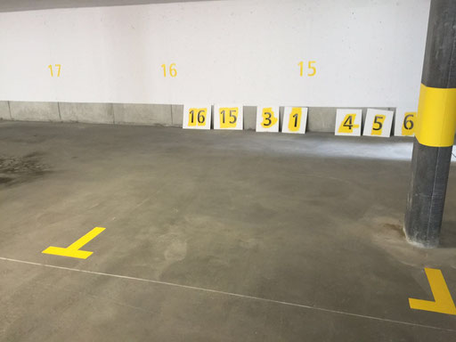 Parkplatzmarkierungen in einer Tiefgarage mit nummerierten Parkplätzen