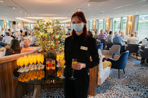 Kellnerin Lena reicht den Gästen ein Glas Sekt