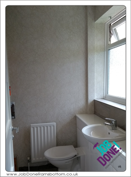 Downstairs toilet; wallpapered, tiled splash back and window sill.