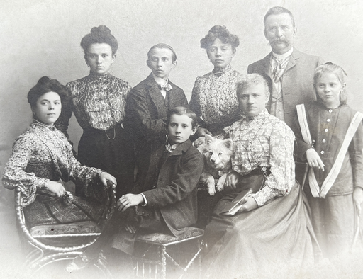 Ein weißer Deutscher Spitz inmitten seiner Familie auf einer Studio-Fotografie aus dem Foto-Atelier Samson & Co., Neuhauserstraße 7 in München, vintage