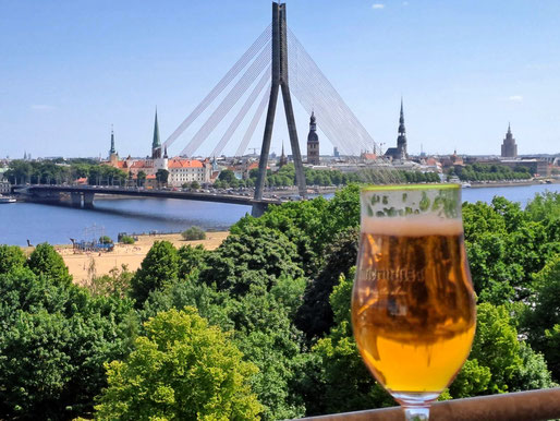 View of Riga skyline on a sunny day from top floor bar of Islande Hotel with a glass of beer in the foreground