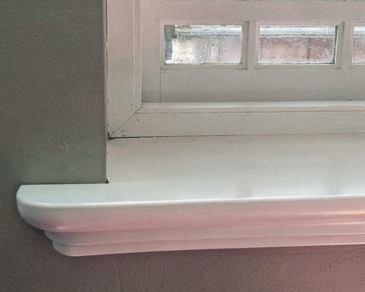 Holzfensterbank mit Profil GRAVENSTEIN in RAL 9016 weiß lackiert eingebaut vor einem älteren Fenster mit kleinen, untereteilten Scheiben