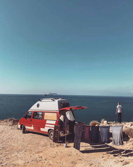 VW Bus mit Wäscheleine steht an der Küste in Griechenland mit Meerblick