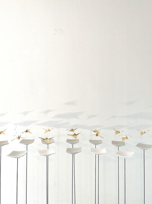 Ein Ausschnitt der Installation Atmosphäre und die Schönheit der Natur. Handgefaltete Kraniche, Origami, aus japanischem Papier, vergoldet. Schwebend gehängt über flache japanische Betonschalen, montiert auf Eisenstäben.