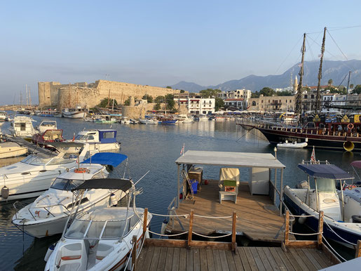 porticciolo con barchette e fortezza in pietra sullo sfondo