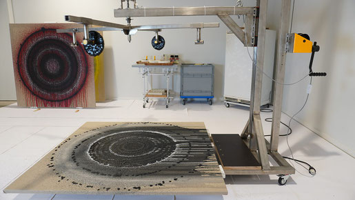 Melting Targets No. 4 — renewed installation with adjustable metal structure above a canvas where black concentric paint circles emerge during the exhibition Transformation Studio No. 1: warm or cold.