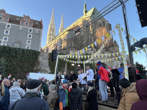 Auf der Bühne sprechen Bäckereiexperten zum Publikum der Mohnstollenverkostung. Im Hintergrund befindet sich die Peterskirche in Görlitz.