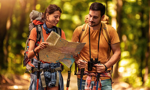 Zwei fröhliche Wanderer mit Karte und Wanderausstattung im goldenen Sonnenlicht