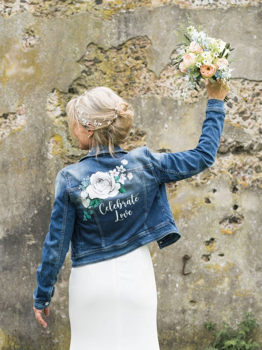 Bruid met gepersonaliseerd spijkerjasje met bloemen en tekst op trouwdag
