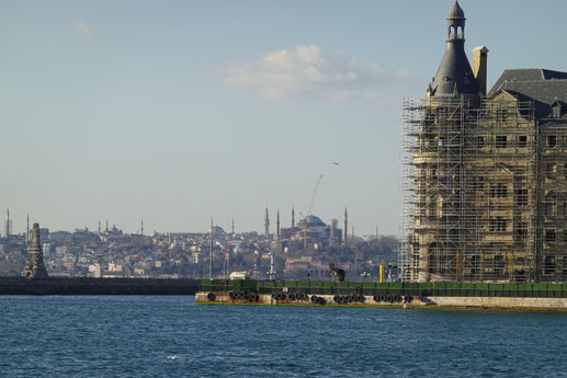 Blick von der Hafenkante in Kadıköy nach Europa, davor auf einer Landzunge der eingerüstete Bahnhof Haydarpaşa
