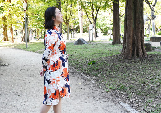 公園を歩く柄のワンピースの女性