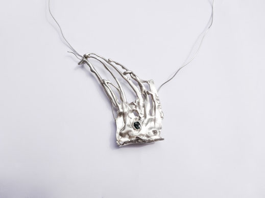 Un collier en argent avec un design qui ressemble à de l'herbe est exposé sur fond blanc.