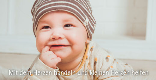 ein kleinkind liegend mit mütze und finger im mund