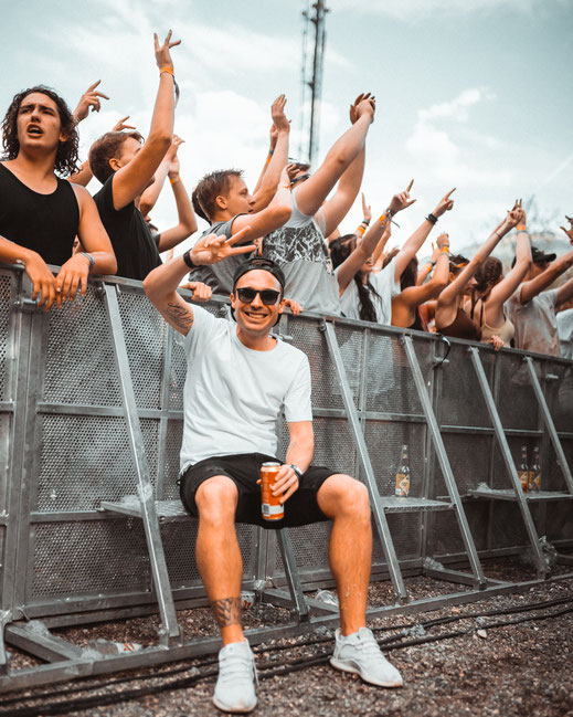 DJ Pat at a festival, sitting infrongt of party crowd