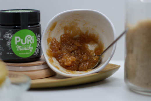 Gommage visage au Miel de Manuka préparation avec pot de Miel de Manuka 240g Puri New Zealand et le Miel touillé dans un bol blanc avec cuillère en métal