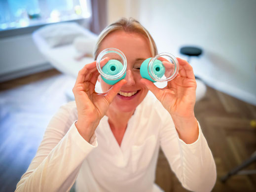 Heilpraktikerin Anne-Kathrin Harders faxt mit Schröpfgläsern vor ihrem Gesicht