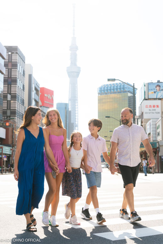 Smiling family walking hand in hand in Asakusa with the Tokyo Skytree in the background