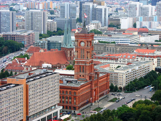 Sehenswürdigkeiten Berlin: Auf dem Roten Rathaus weht die Fahne der Stadt Berlin. Der hohe Turm des Rathauses überragt die umliegenden Gebäude und sogar die beiden Kirchtürme der nahegelegenen Nikolaikirche.