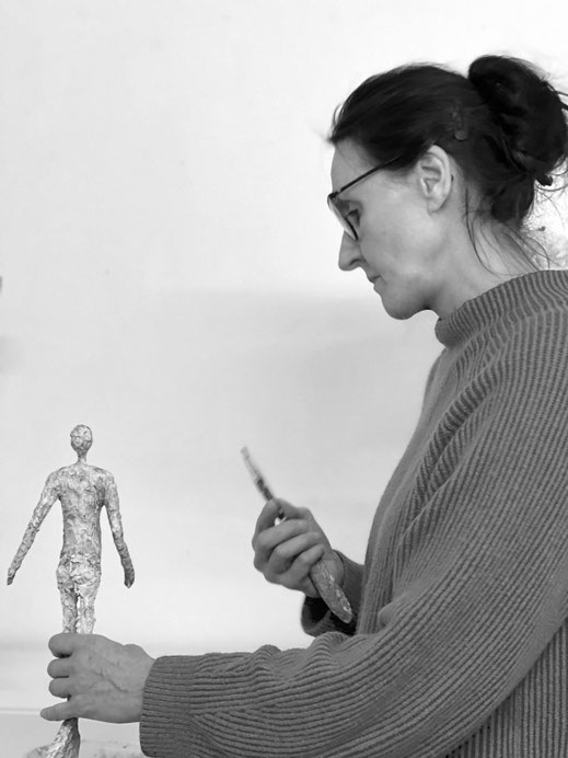 Künstlerin Claudia König bei der Arbeit an einer monochromen Figur in ihrem Atelier.