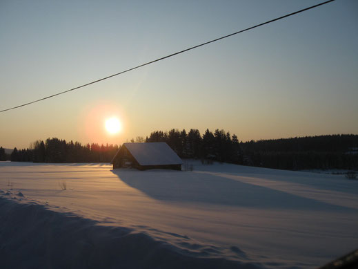 De middagzon boven het besneeuwde land, met schuur