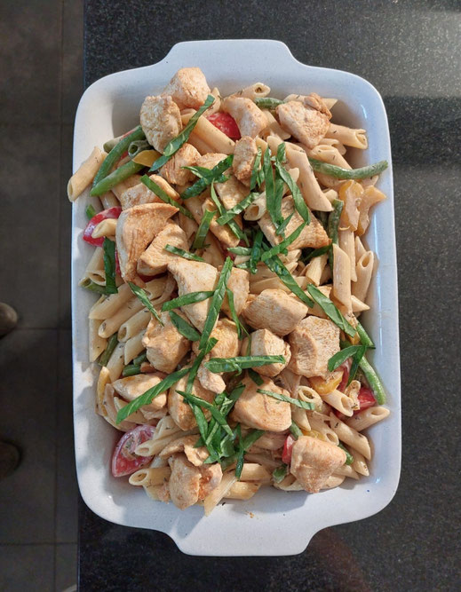 Gekochte Penne mit gebratenen Hühnchenwürfeln, Tomaten und Bohnen