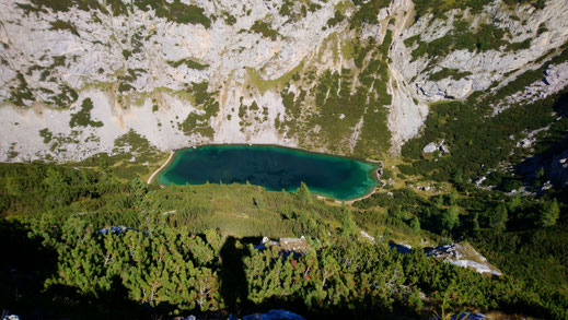 Blick von oben auf den grünen Silberkarsee im Dachsteingebirge umgeben von steilen Fels- und Geröllhängen