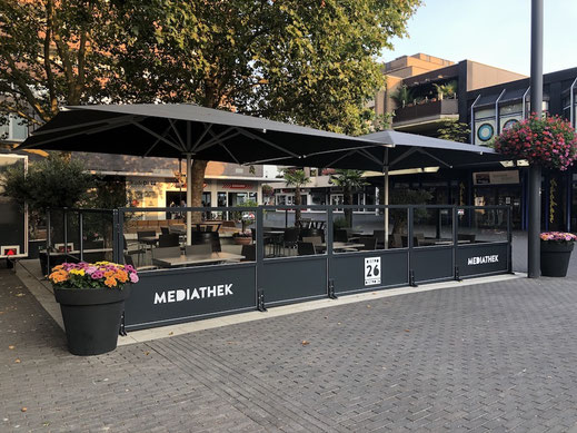 Windschutz-System für Außengastronomie, hochwertige Glaswand für Terrassen mit Gastronomie-Branding und Sonnenschirmen