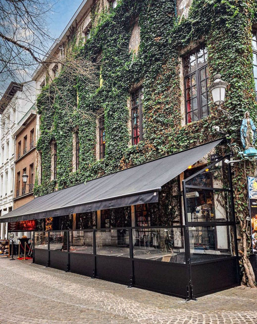 Moderne Gastronomie-Terrasse mit Windschutz-System und Markise vor einer historischen Fassade