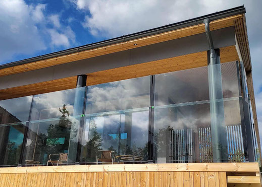 Glas-Balustrade auf Holzterrasse – transparente Absturzsicherung mit Windschutz für exklusive Gastronomie-Außenbereiche