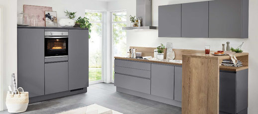 Moderne Einbauküche in Grau mit Holzarbeitsplatte, integriertem Backofen und viel Tageslicht – zeitloses, funktionales Küchendesign mit Stauraum und großzügiger Arbeitsfläche.