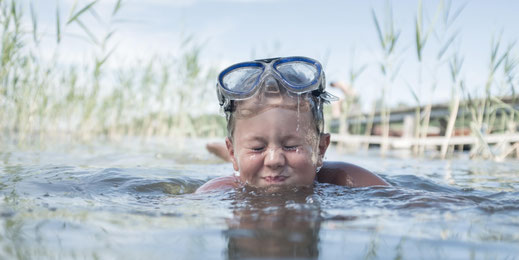 Sommerurlaub im Salzkammergut – Kind beim Schwimmen im klaren See