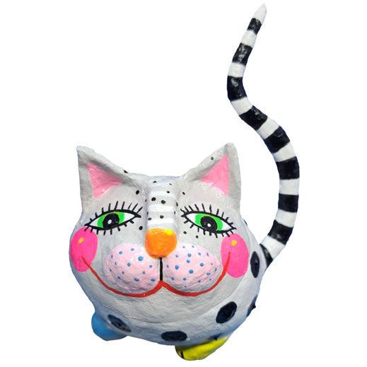 Handgefertigte Pappmaché-Katzenfigur in hellgrau mit großen schwarzen Punkten und rosa Wangen. Sie hat grüne Augen mit Wimpern, eine orange Nase und einen schwarz-weiß gestreiften Schwanz. Bunte Pfoten gelb und türkis..
