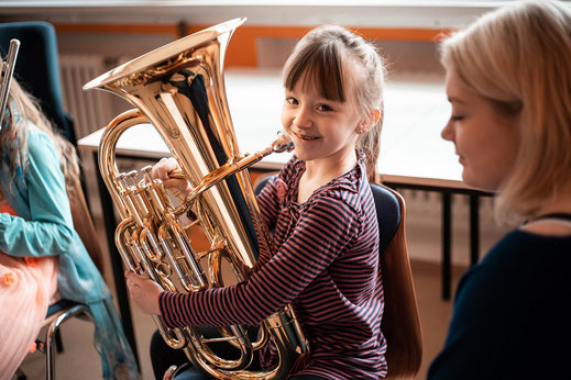 Eine junge Tubistin des Musaik-Orchesters lächelt in die Kamera.