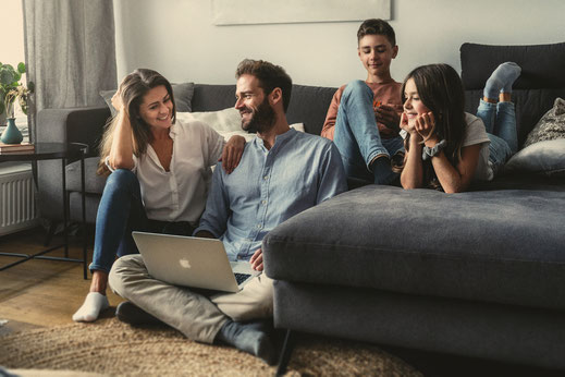 Familie sitzt gemeinsam auf dem Sofa im Wohnzimmer und genießt einen ruhigen Moment – authentisches Familienshooting in Osnabrück.