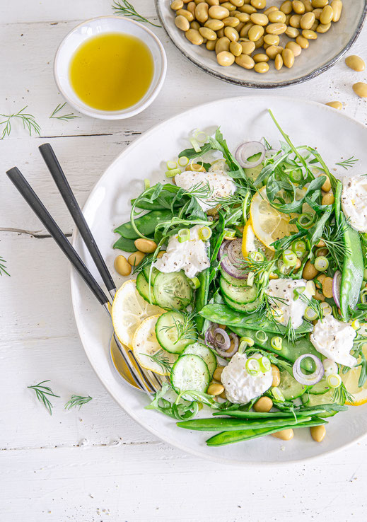 Frühlingssalat mit Rucola, Zuckererbsen, Edamame und Burrata auf einer Servierplatte