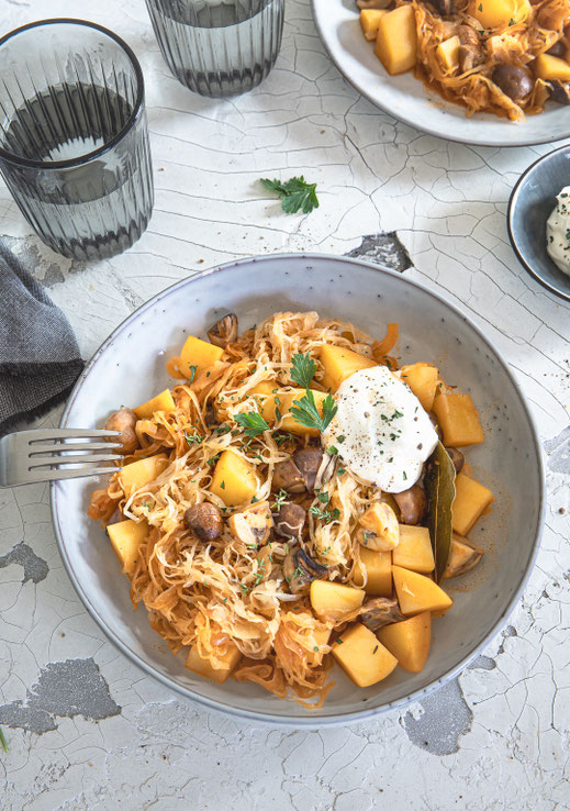 Deftiger vegetarischer Szegediner Kartoffelkraut-Eintopf mit Champignons, Kartoffeln und Sauerkraut in einer Schale serviert
