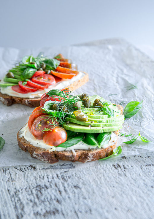 Dinkelvollkornbrot mit cremigem Frischkäse, frischen Tomaten, Avocado und Kräutern