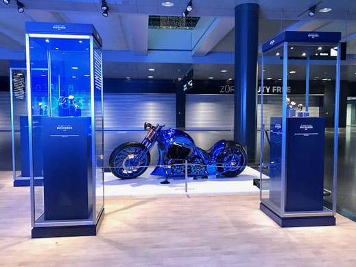 A blue Harley Davidson motorcycle on display between two showcases