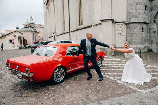 Hochzeit Trauung Hall in Tirol Standesamt Eintreffen der Braut in Ford Mustang am Oberen Stadtplatz lustige Fotos Spaß Braut zieht Bräutigam von Auto weg