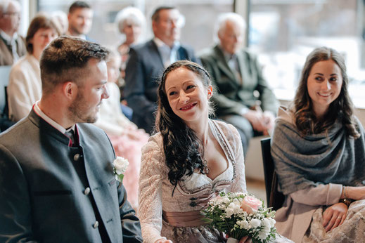 Hochzeit Sistrans Standesamt Trauung Braut lächelt Bräutigam an Trauzeugin und Gäste im Hintergrund 